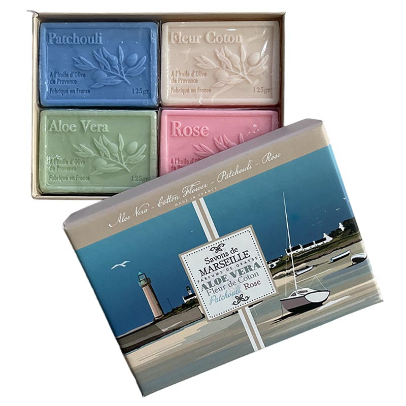 A boxed set of four artisanal soaps displayed with their outer packaging. The soaps are labeled Patchouli, Fleur Coton, Aloe Vera, and Rose in blue, beige, green, and pink.