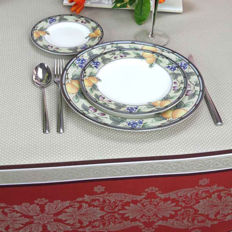 Set of floral-patterned plates with silverware on a decorative tablecloth.