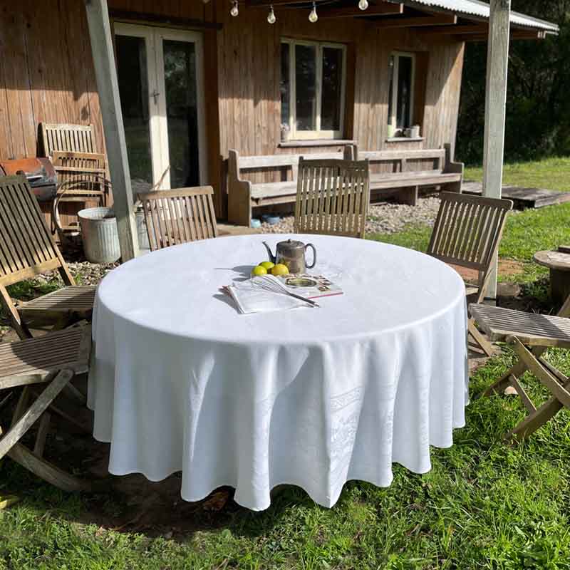 white round jacquard woven tablecloth in front of a rustic timber cabin