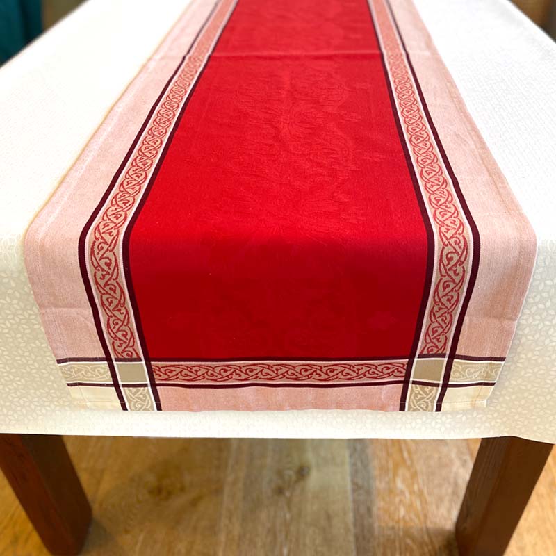 Red table runner with decorative border on a white tablecloth