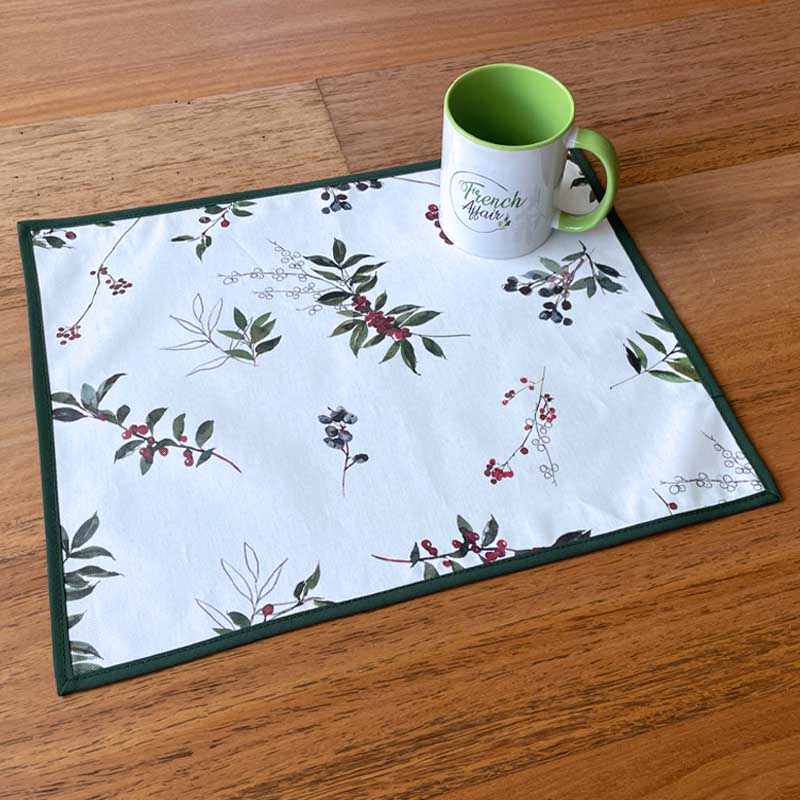 Placemat with floral pattern on a wooden surface with a mug.