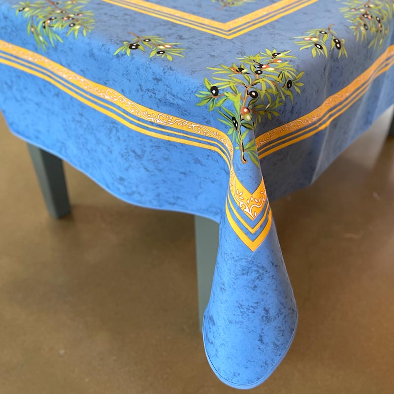 Blue tablecloth with green leaf and olive design on a brown surface