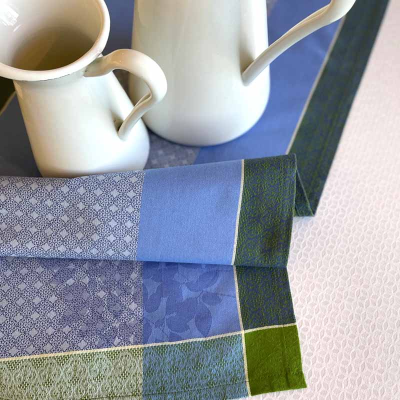 Two white mugs on a blue and green patterned tablecloth.