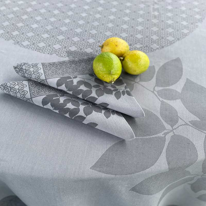 Gray patterned tablecloth with folded napkins and lemons on a matching surface