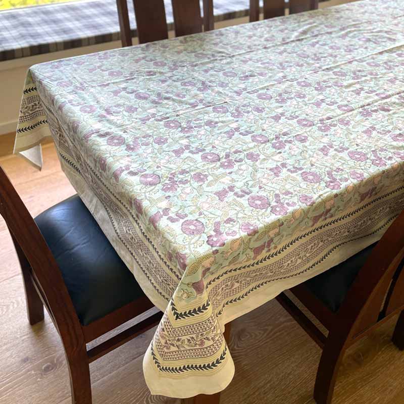 Dining table with a floral tablecloth in a room with wooden flooring.