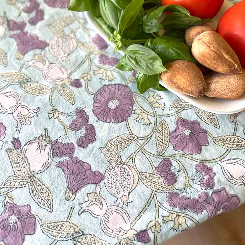 Floral-patterned tablecloth with a bowl of bread and tomatoes on a table.