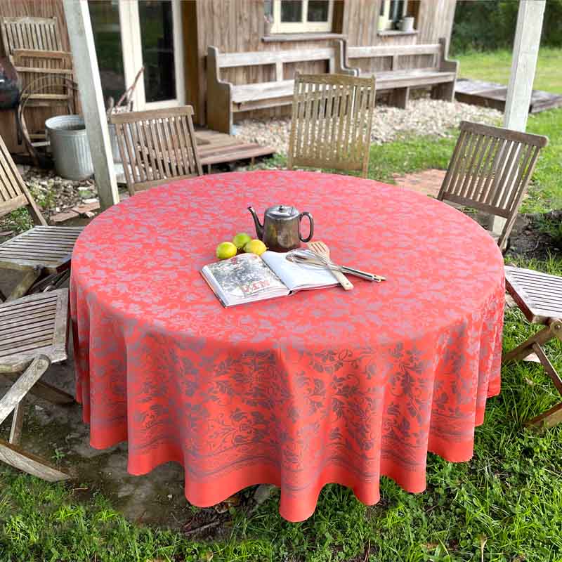Round table with an orange design and border outdoors, surrounded by chairs.