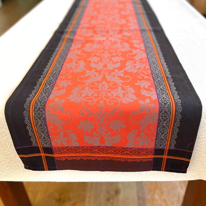 Decorative table runner with red and black pattern on a white surface