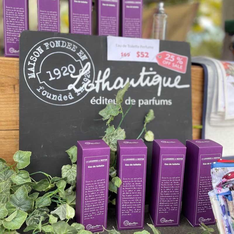 L'Artisan Parfumeur products displayed with a blackboard sign in a store setting.