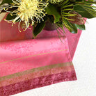 Pink fabric with floral patterns and a bouquet of flowers on a white background