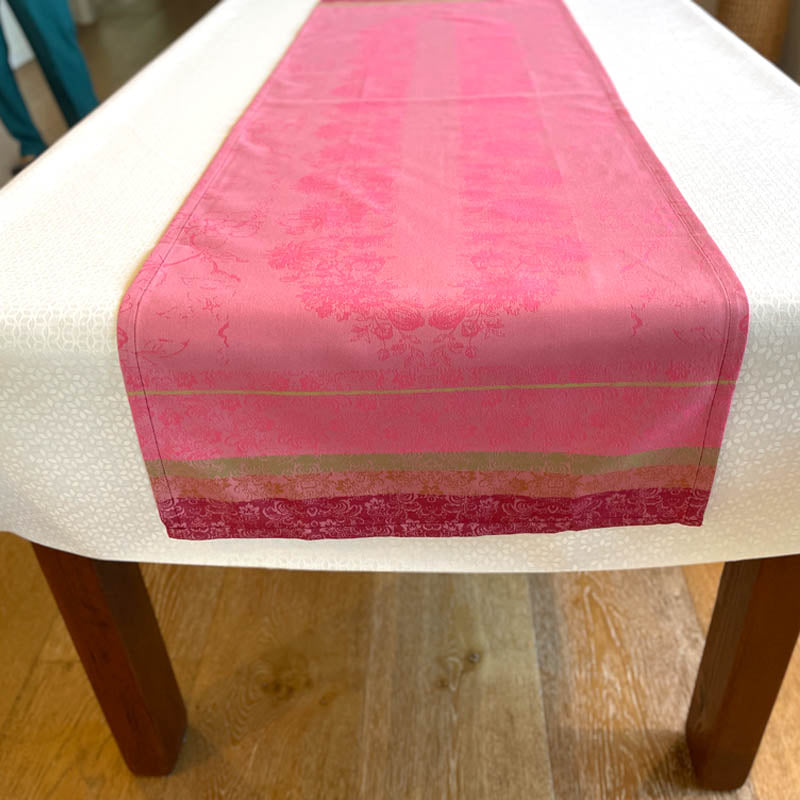 Pink table runner on a wooden table with a white surface