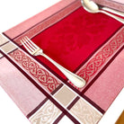 Decorative placemat with red center, gold border, and silver fork.