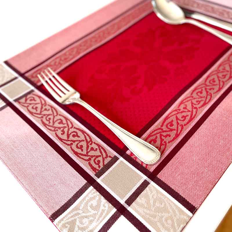 Decorative placemat with red center, gold border, and silver fork.