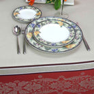 Set of floral-patterned plates with silverware on a decorative tablecloth.