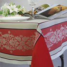 Table setting with a red and fawn patterned tablecloth, plate, and glass.