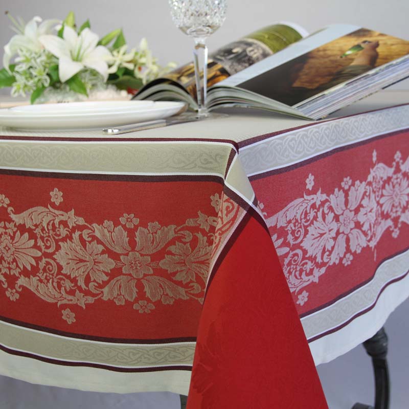 Table setting with a red and fawn patterned tablecloth, plate, and glass.