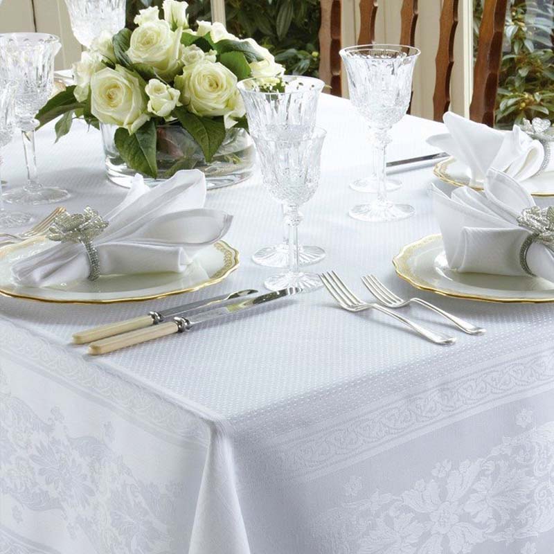 Elegant table setting with white tablecloth, silverware, and floral centerpiece.