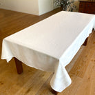 White tablecloth on a wooden table in a room with wooden flooring.