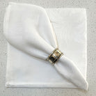 White jacquard napkin with napkin ring sitting on another white napkin