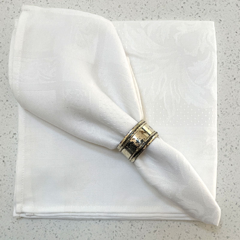 White jacquard napkin with napkin ring sitting on another white napkin
