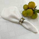 White napkin with a silver ring and lemons on a white tablecloth