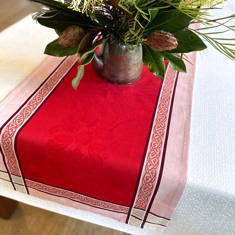 Red table runner with a floral pattern on a white surface