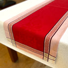 Red table runner with decorative border on a white table