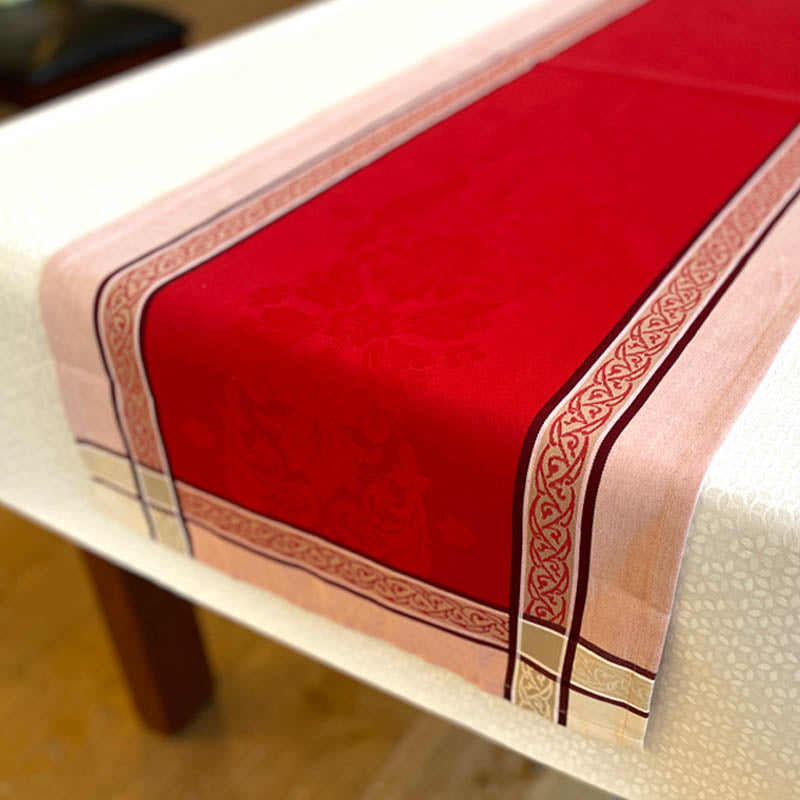 Red table runner with decorative border on a white table
