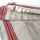 A folded linen kitchen towel with red and white stripes and a gray printed design, showing the brand name 'Dormont & Company' and 'Cannes' on the fabric.