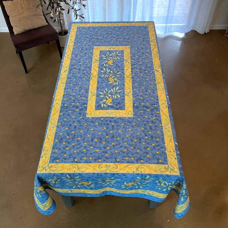 Blue tablecloth with yellow border on a wooden table in a room.