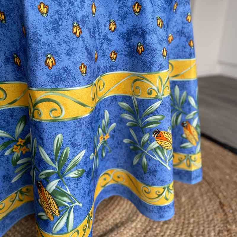Blue tablecloth with yellow and green patterns featuring cicadas and leaves.