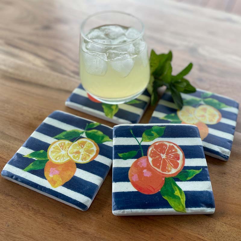 Set of 4 resin drink coasters in Citrus Blue design. Cork backing. Oranges and lemons on a navy blue and white striped background.