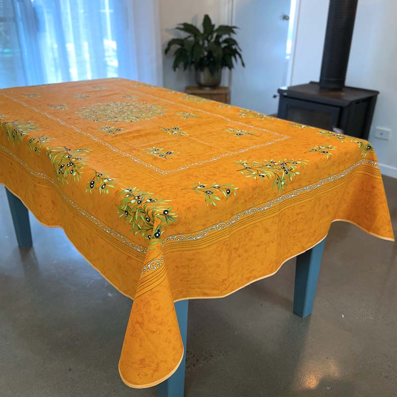 Orange tablecloth with floral patterns on a blue table in a room.