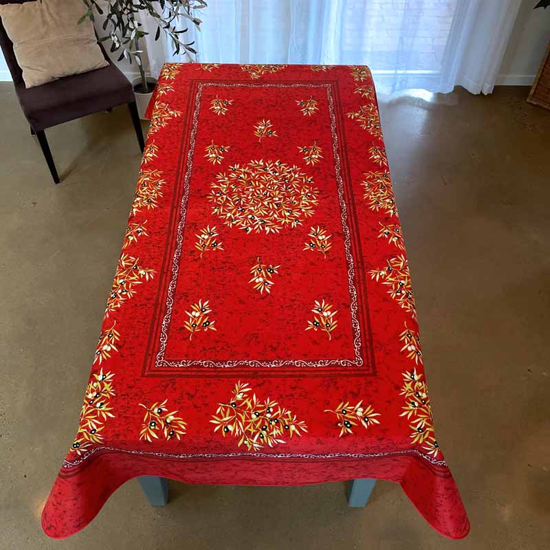 Red tablecloth with gold floral patterns on a wooden table in a room.