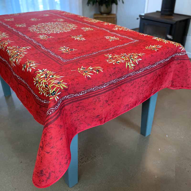 Red tablecloth with floral patterns on a table in a room.