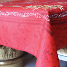 Corner of a red tablecloth with olive patterns on a table