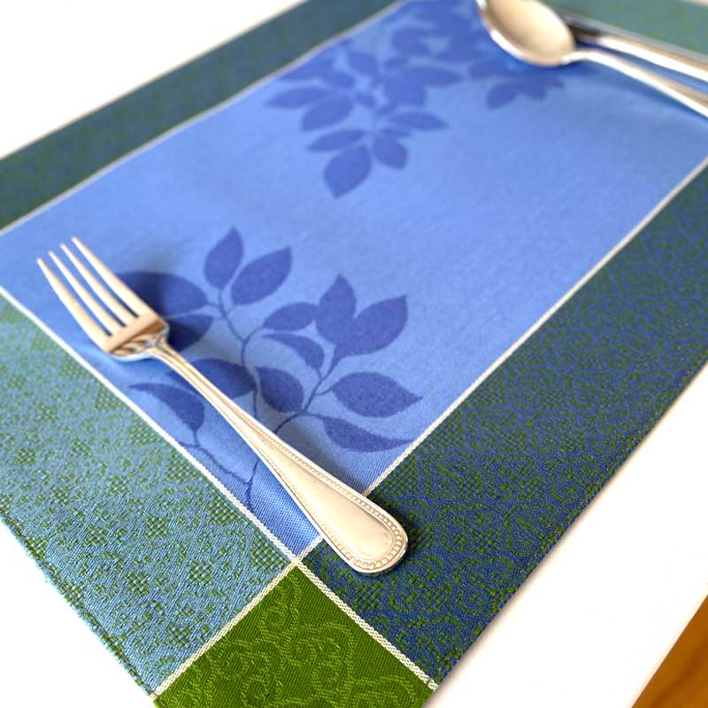 Blue and green patterned placemat with a fork and spoon on a white surface