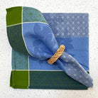 Folded fabric napkin with a decorative ring on a textured surface