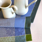 Two white mugs on a blue and green patterned tablecloth.