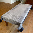 Tablecloth with a leaf pattern on a wooden table in a room.