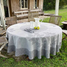 Round table with a patterned tablecloth outdoors in a garden setting