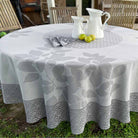 Round table with a gray floral patterned tablecloth outdoors.