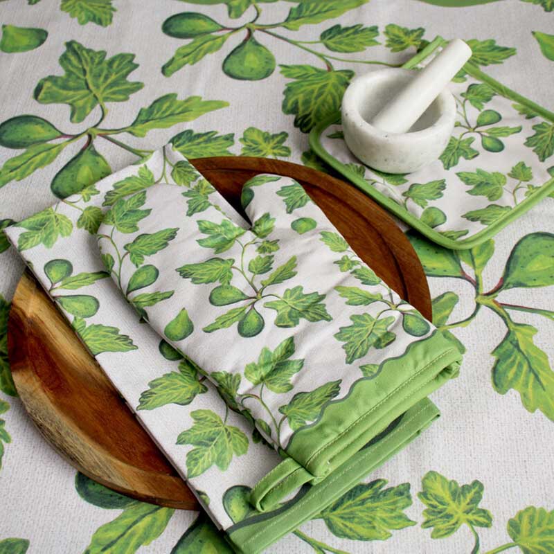 Folded green leaf-patterned fabric on a matching tablecloth with a white mortar and pestle.