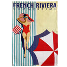 A waffle-weave tea towel featuring a retro French Riviera summer beach illustration with the text 'FRENCH RIVIERA SUMMERTIME' at the top, a woman in a red swimsuit and striped hat, and a red, white, and navy umbrella on a cream background.