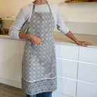 Person wearing a grey patterned apron in a kitchen setting