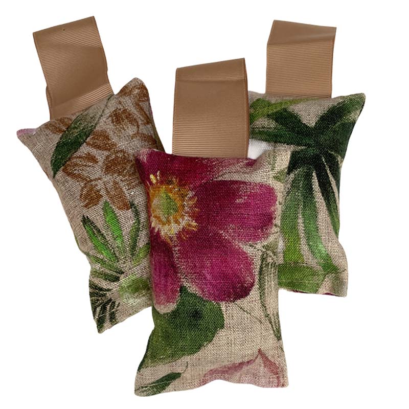 Three small hanging lavender sachets with flower and leaf pattern and gold hanging ribbon. On a white background.