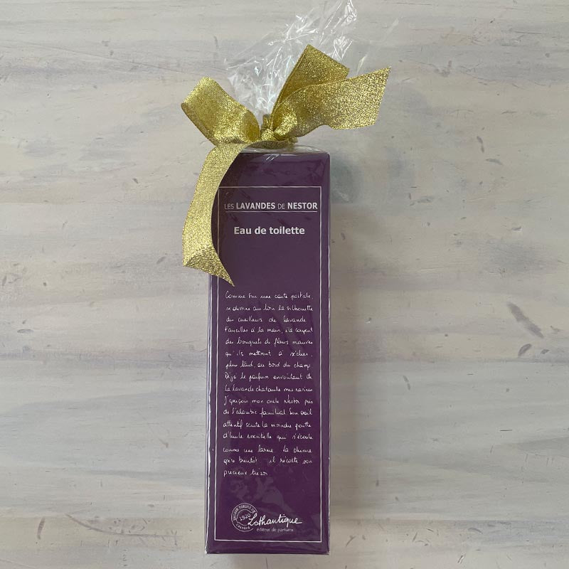 Purple Eau de Toilette bottle with gold bow on a light wooden surface