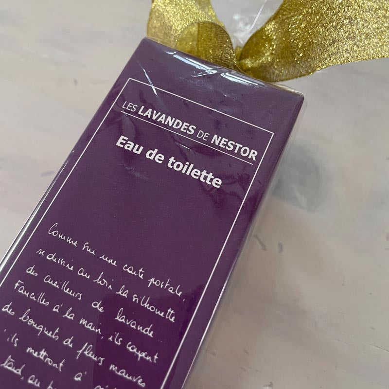 Purple box of 'Eau de Toilette' with gold ribbon on a light background