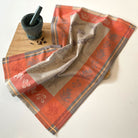Decorative red and beige towel with floral patterns on a wooden cutting board.