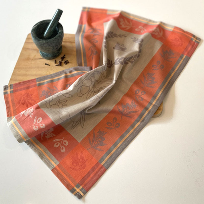 Decorative red and beige towel with floral patterns on a wooden cutting board.